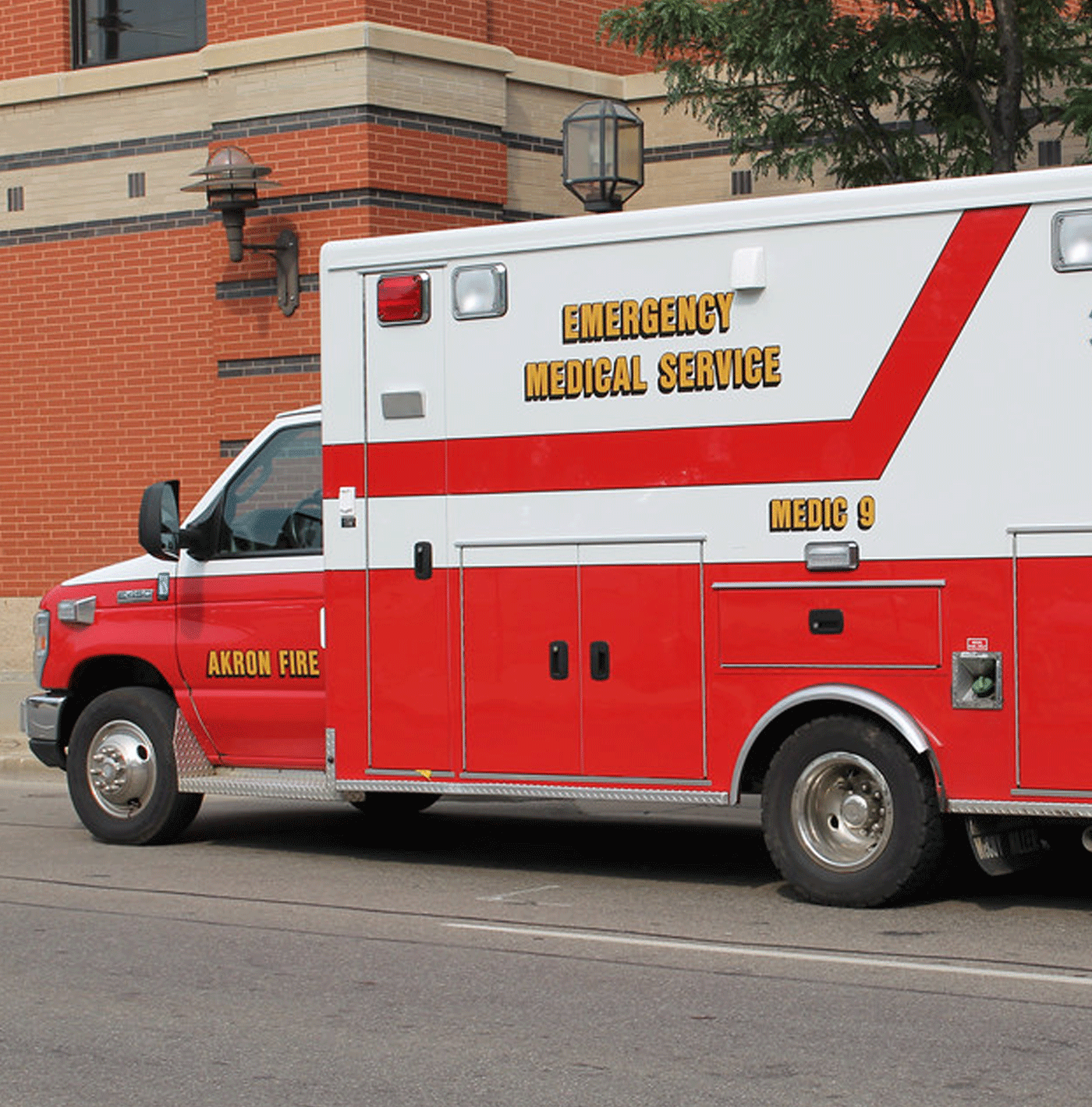 A large red and white ambulance parked in front of a medical facility.