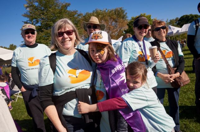 A family in matching t-shirts group-hugs at the Rise Above Seizures walk.