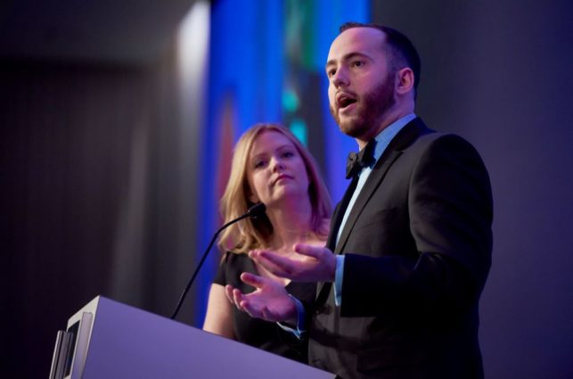Two people wearing fancy clothes give a speech at a podium during the Epilepsy Foundation gala.