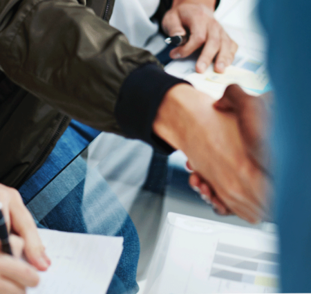 Close up of two people shaking hands over a table, representing jobs for people with epilepsy.