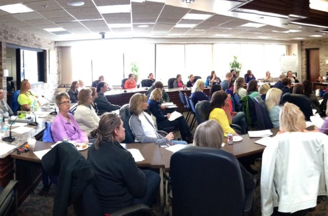 Conference room with a large, round table filled with people.