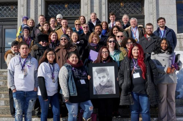 A large group of people stand together on the steps of the state capitol building.