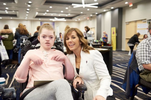 A person in a wheelchair and a woman next to them smiling for the camera.