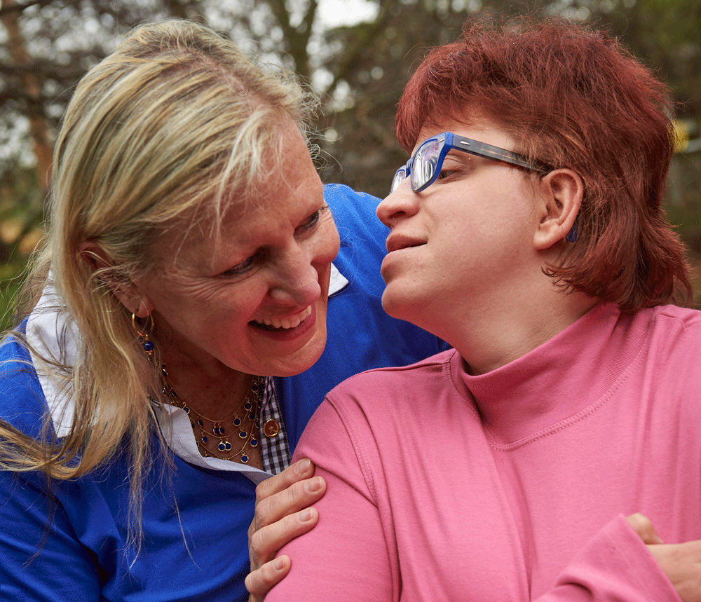 A mother leans in to get a kiss on the cheek from her daughter.