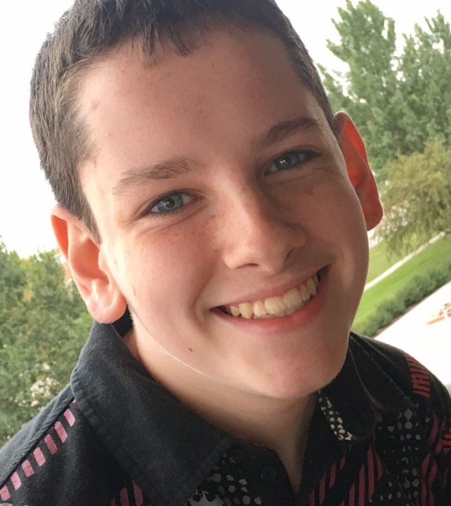 Close-up headshot of a middle-school aged boy smiling at the camera