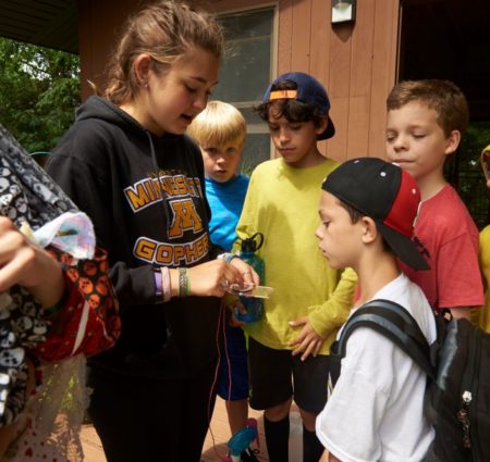 An older child shows a craft to a group of younger children.