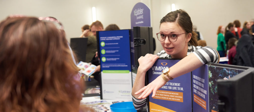 Mid 20's woman speaking with a visitor at epilepsy expo