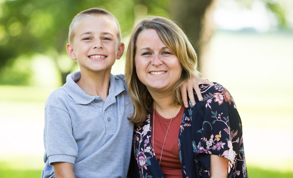 Blonde haired mom in a floral shirt smiles with her 12 year old son