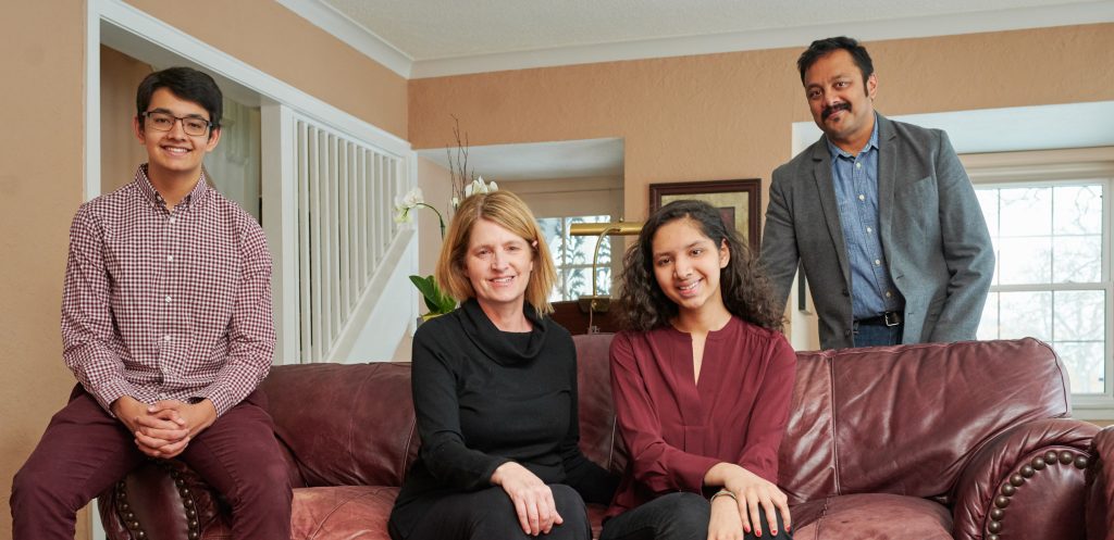 Husband, wife, son, daughter sitting on couch smiling