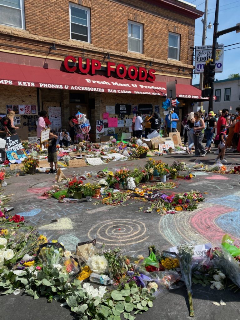 Outdoor memorial with people and flowers