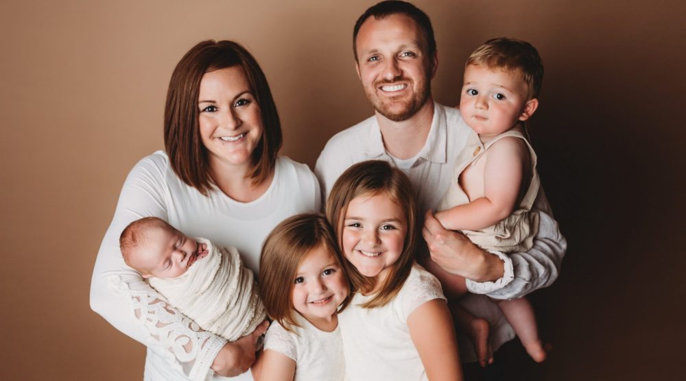 Husband and wife pose with their four children