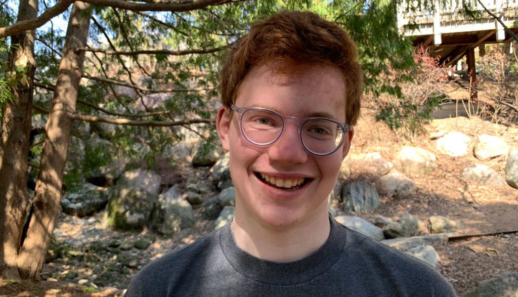 teenage boy smiling at camera outside