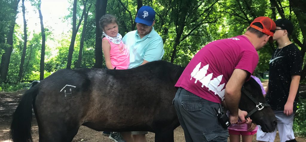 young girl being held up by horse