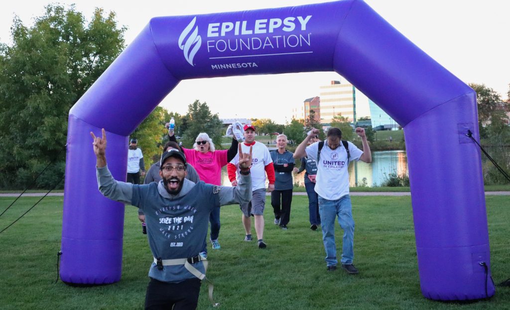 man running through balloon arch excited