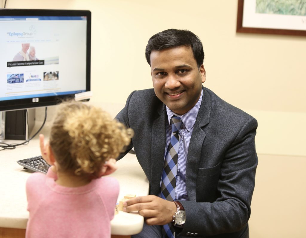 Dr. Nitin Agarwal at desk with child patient