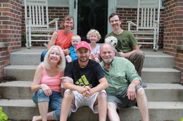 family of 7 sit on front steps of house