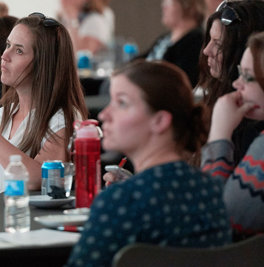 A group of people around a table listens during a training.