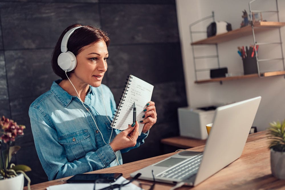 Women sitting in front of computer with headphones on