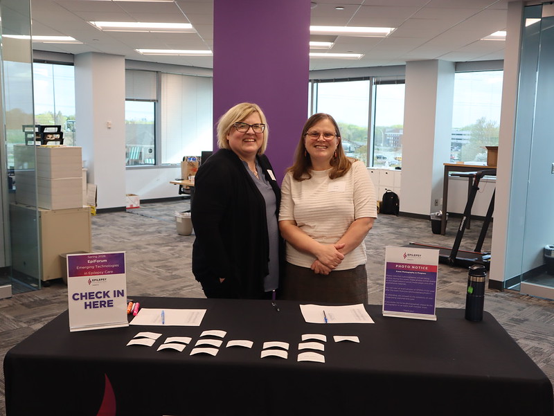 EFMN Staff members at an EpiForum check-in table smiling for a picture in the EFMN office