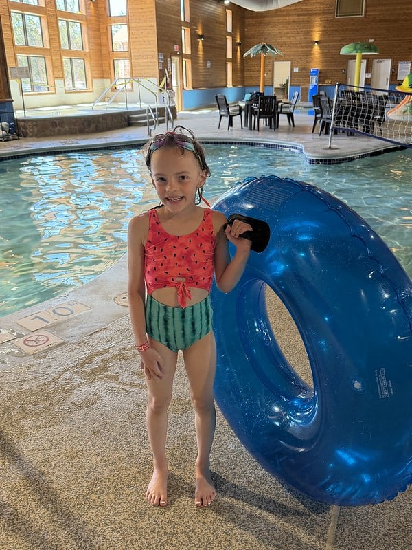 Attendee with an inner tube by the pool at the waterpark wearing goggles on forehead