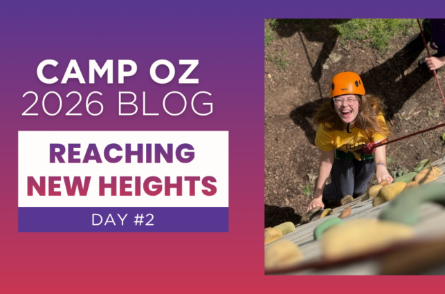 Person wearing an orange helmet climbs a camp rock wall outdoors, looking upward while secured with a rope, next to text reading “Camp Oz 2026 Blog — Reaching New Heights Day #2” on a purple gradient background.