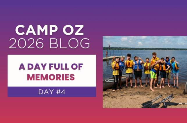 Camp Oz 2026 Blog – A Day Full of Memories, Day #4” featuring a group of campers wearing life jackets standing together on a lakeshore next to canoes and paddles, with a dock and calm water in the background under a partly cloudy sky