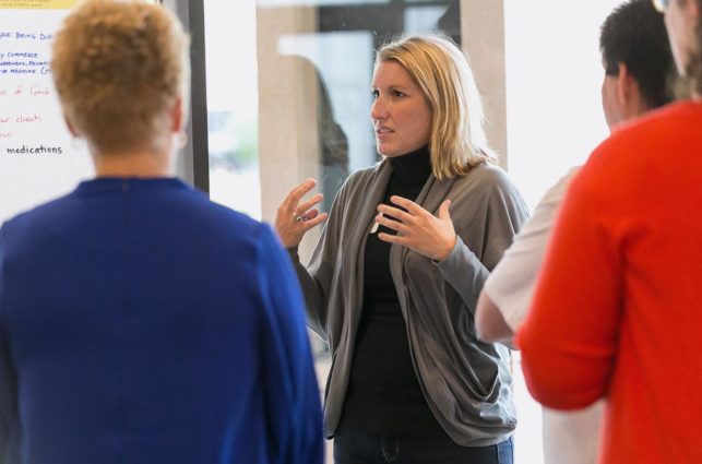 Woman gesturing with her hands to a group of people.